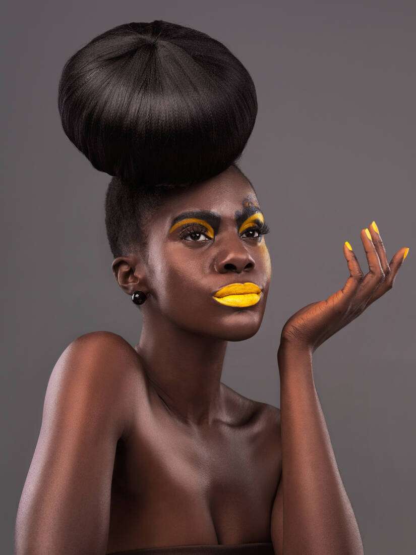 A woman with a sculpted updo and golden makeup, poised and regal