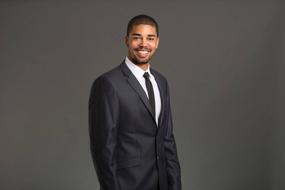 A smiling young man in a dark suit