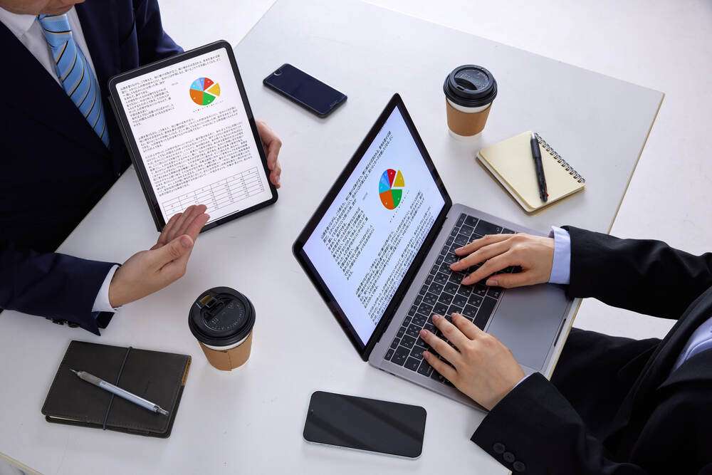 Business documents with charts on a tablet and laptop