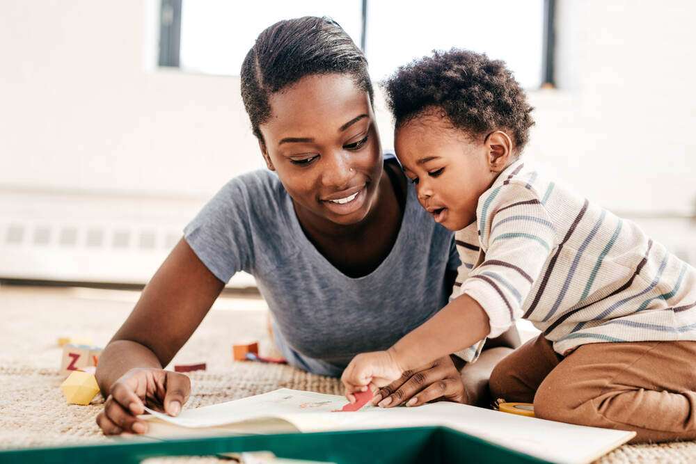 A mother reading with her baby on the floor