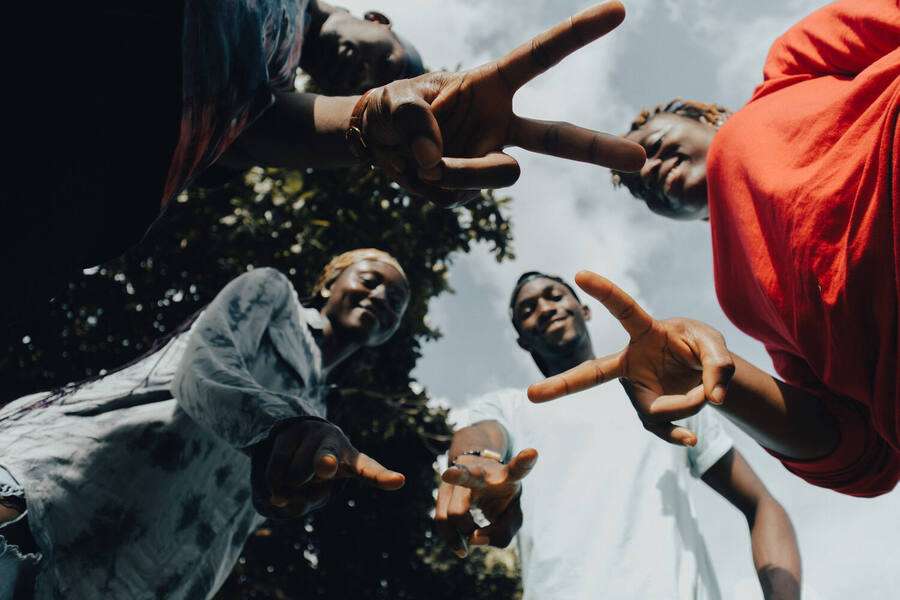 Young Black friends standing in a circle, reaching toward the camera