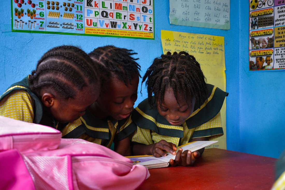 Three young girls reading together at a classroom table