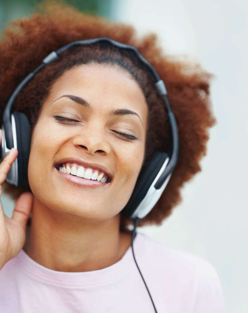 A smiling woman listening with headphones, eyes closed