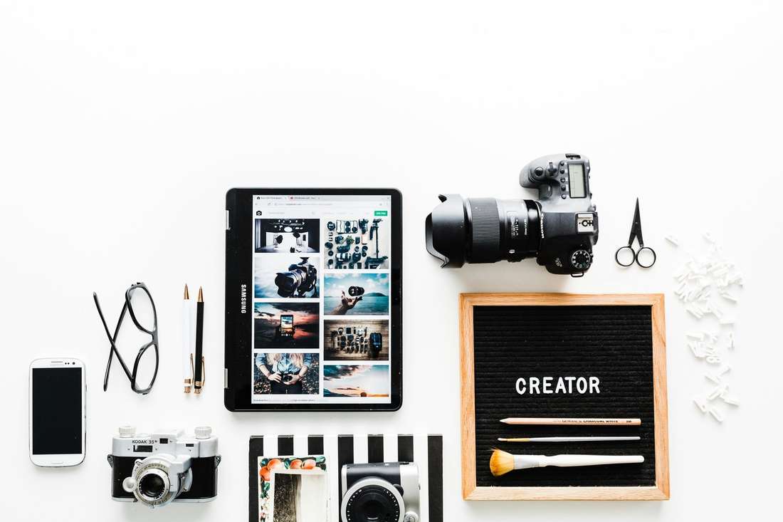 A creator's desk with a camera, letter board reading CREATOR, and film cameras