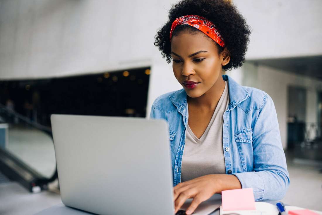 A woman in a red headband typing on her laptop