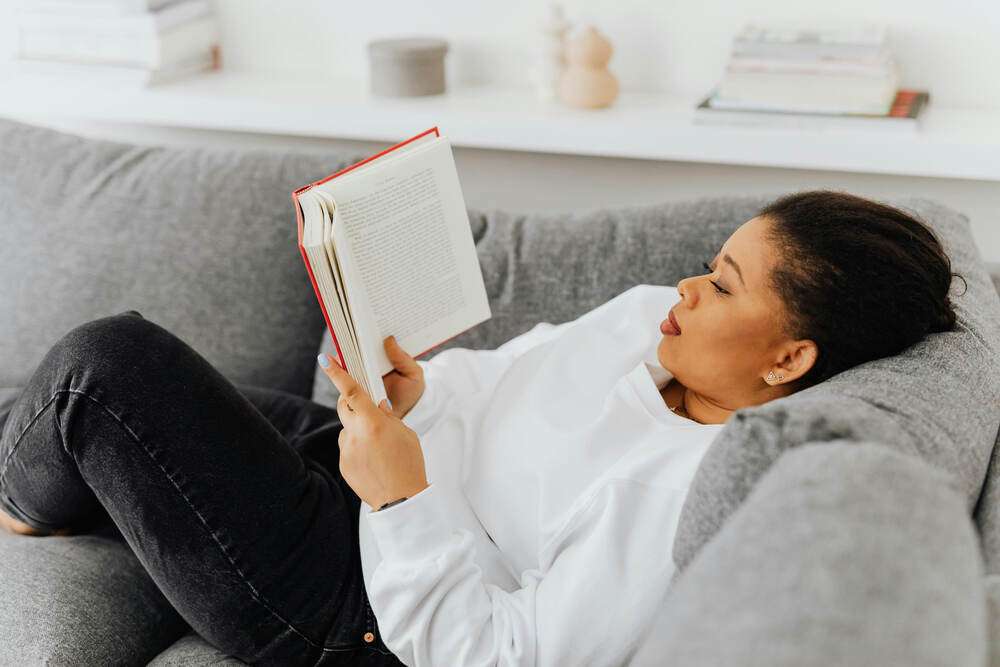 A woman relaxing on her couch reading a book