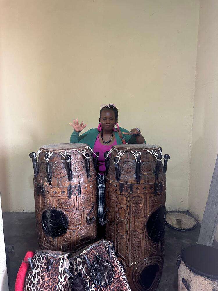 Kathy playing large carved talking drums at the Asokore King's Palace in Ghana